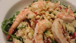 Serve the couscous salad over a bed of greens and garnish with toasted pine nuts (Photo Credit: Adroit Ideals)