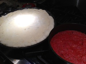 Pizza dough rests on the pan while roasted tomato sauce simmers  (Photo Credit: Adroit Ideals)