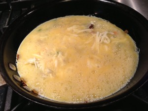 Add the egg mixture to the pan over the vegetable and cheese mixture (Photo Credit: Adroit Ideals)
