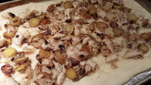 Garlic chicken, sauteed fingerling potatoes, roasted garlic cloves wait for mozzarella topping on a pizza crust  (Photo Credit: Adroit Ideals)