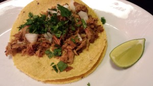 Traditional Pork Carnitas Tacos are served on corn tortillas with cilantro and raw onion. Season with a squeeze of lime. (Photo Credit: Adroit Ideals)