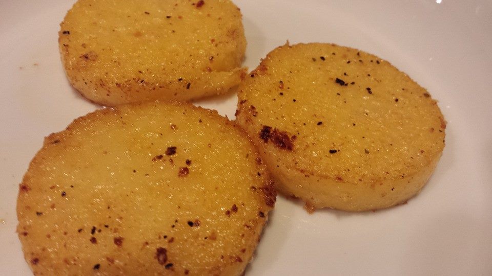 Polenta Slices Sauteed in Garlic Butter are Plated (Photo Credit: Adroit Ideals)