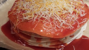 Top the sauced Chicken Enchilada Stack with shredded cheeses  (Photo Credit: Adroit Ideals)
