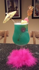 The Blue Hawaiian Cocktail served girly style in a Hurricane glass with an umbrella and fluffy hot pink feather slipper (Photo Credit: Adroit Ideals)
