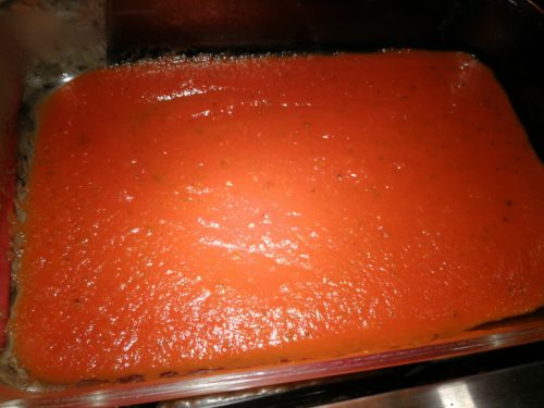 Ladle enchilada sauce onto pan bottom