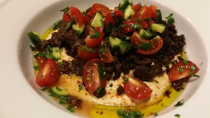 Hummus topped with spicy ground beef, tomato, cucumber, parsley, olive oil