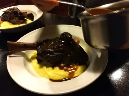 Drape the red wine sauce over the braised lamb shanks