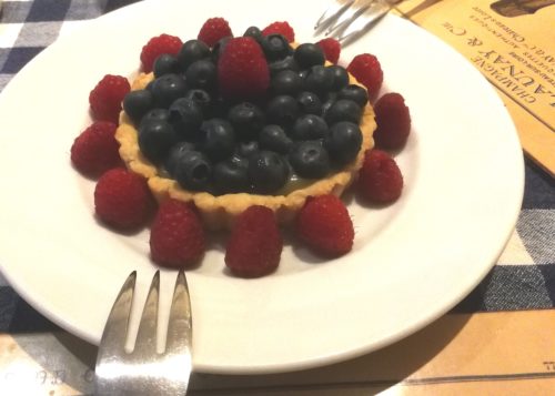 Raspberries garnish a blueberry lemon curd tart