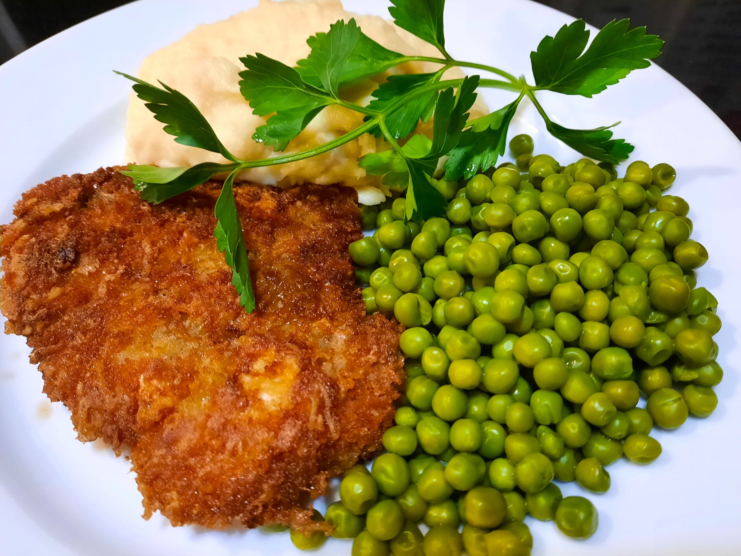 Crispy Pork Schnitzel served with mashed potatoes and peas